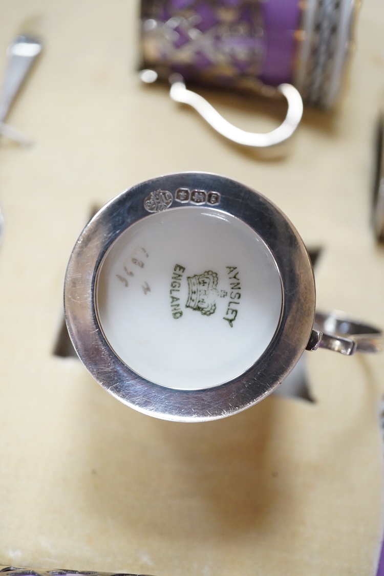 A cased Aynsley coffee set with silver mounted coffee cans and silver teaspoons, William Hutton & Sons, Sheffield, 1924, the leather case 38cm wide